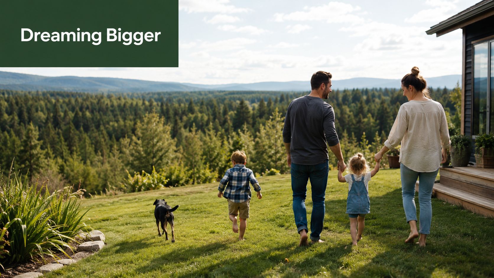 A happy family walking barefoot on a grassy lawn with their dog near a mountain home.